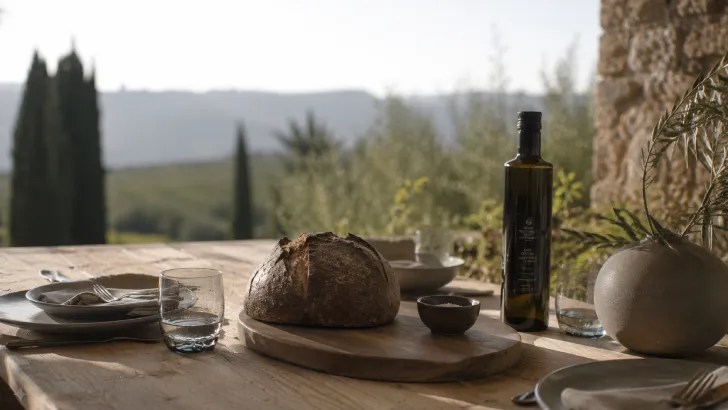 Tavola rustica apparecchiata all'aperto con pane e olio